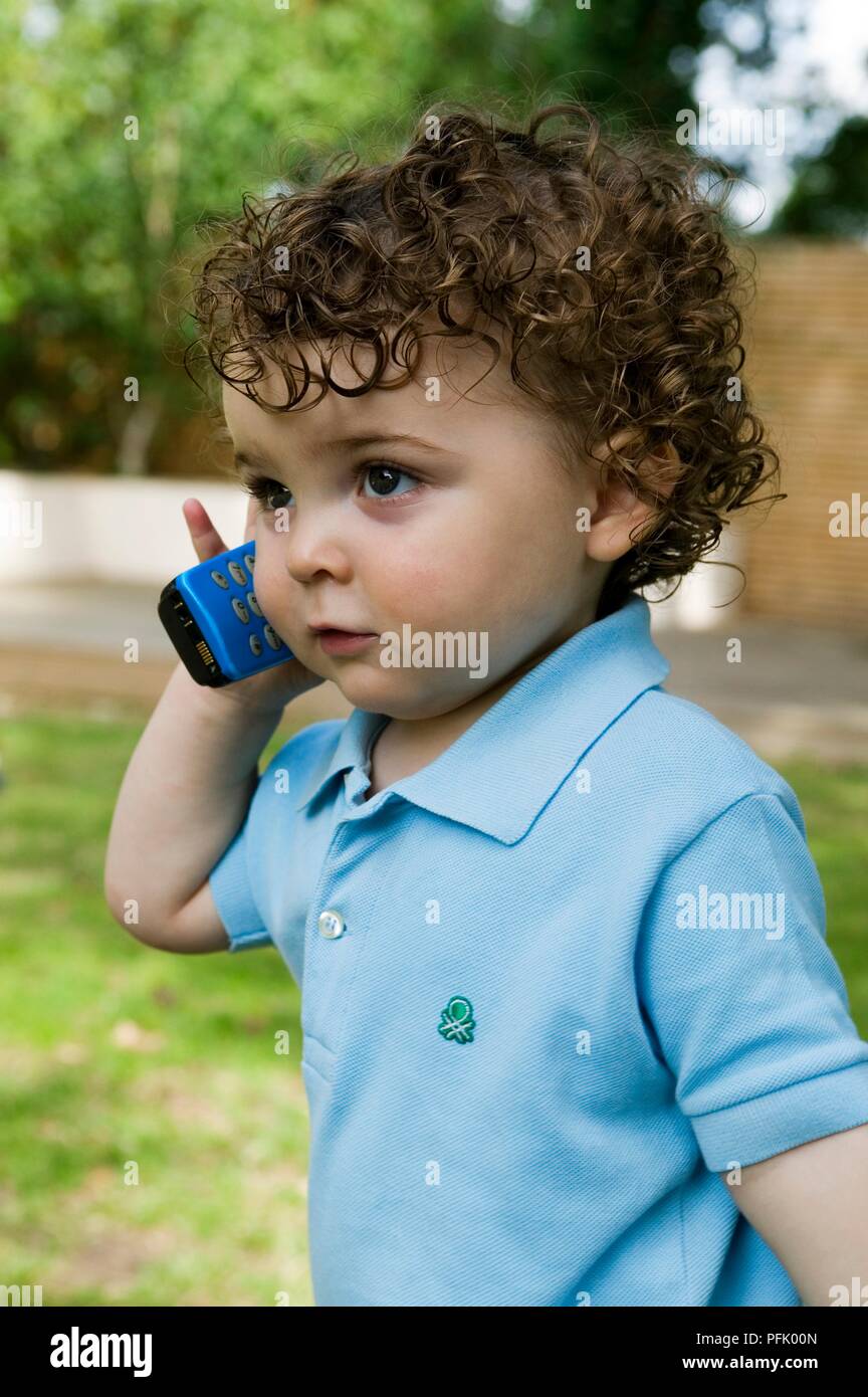 Infante sosteniendo el teléfono móvil a su oído, close-up Foto de stock