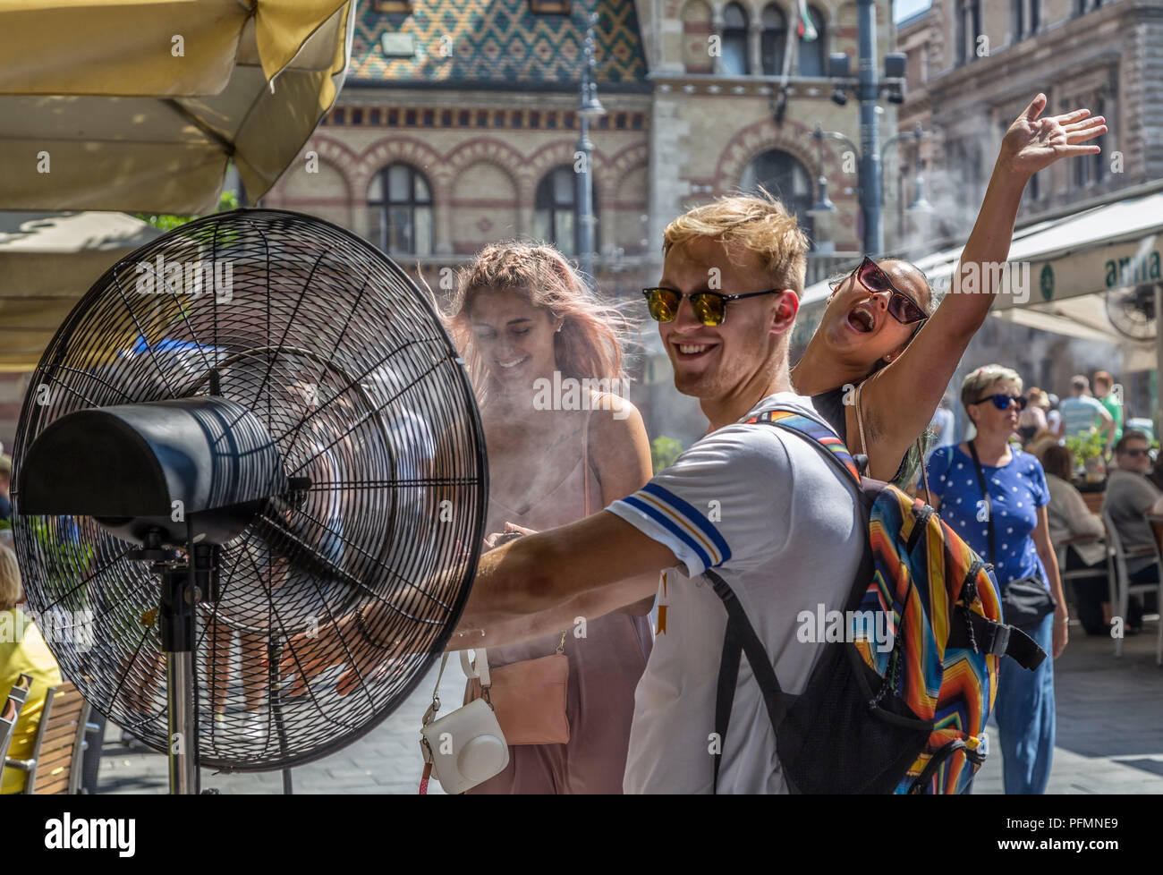 BUDAPEST,Hungría-agosto 09,2018:personas aliviar la ola de calor del verano en la parte delantera de la pulverización de agua ventilador en la calle del centro de la ciudad. Foto de stock