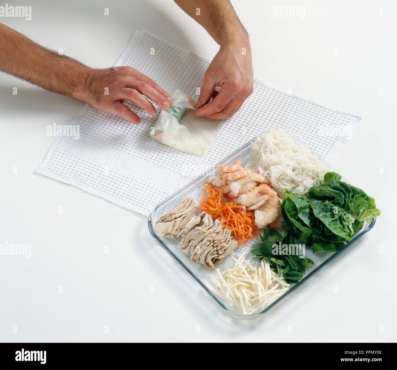 Plegado de papel de arroz húmedo alrededor de ingredientes para los  rollitos de primavera vietnamitas Fotografía de stock - Alamy