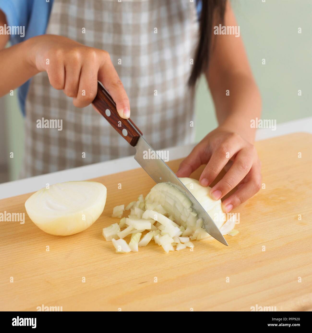 Chica con cuchillo de cocina para picar la cebolla sobre una tabla de cortar  Fotografía de stock - Alamy