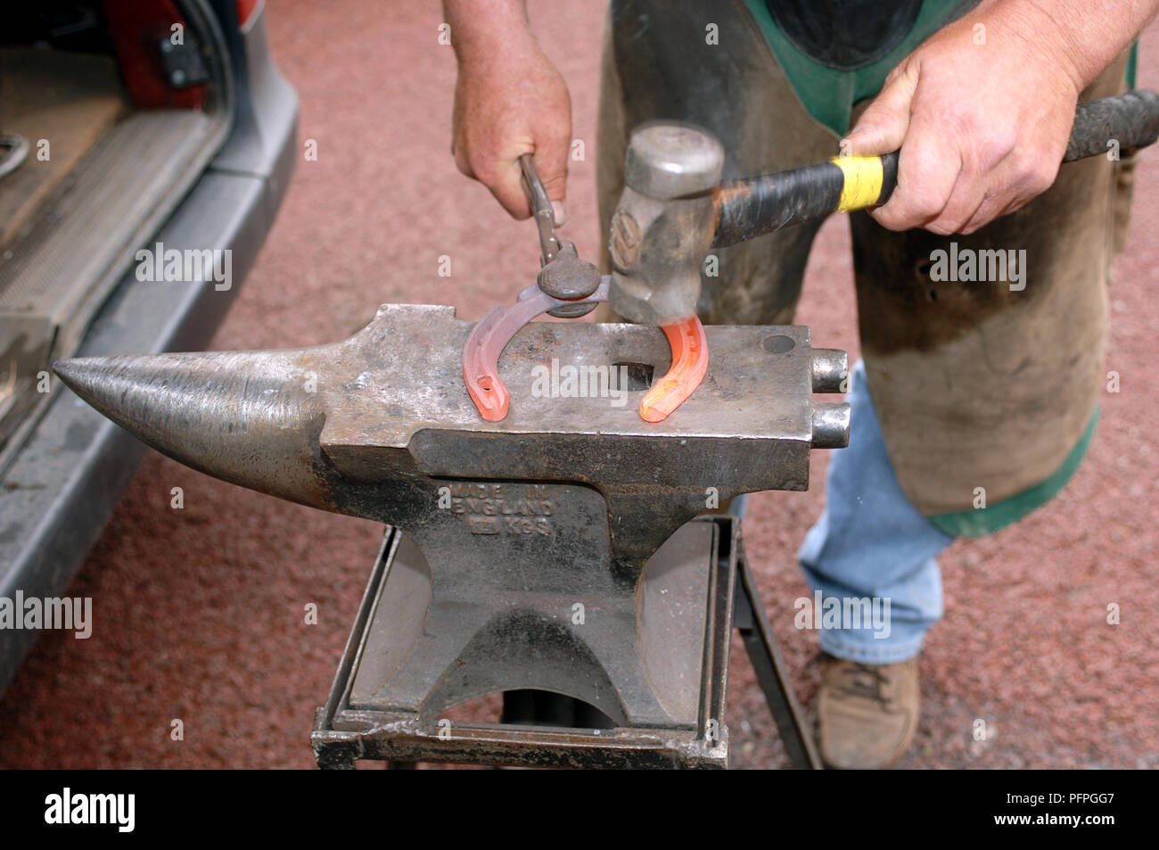 Celebración Farrier rojo-metal caliente con pinzas de herradura sobre el  yunque con un martillo para dar forma Fotografía de stock - Alamy