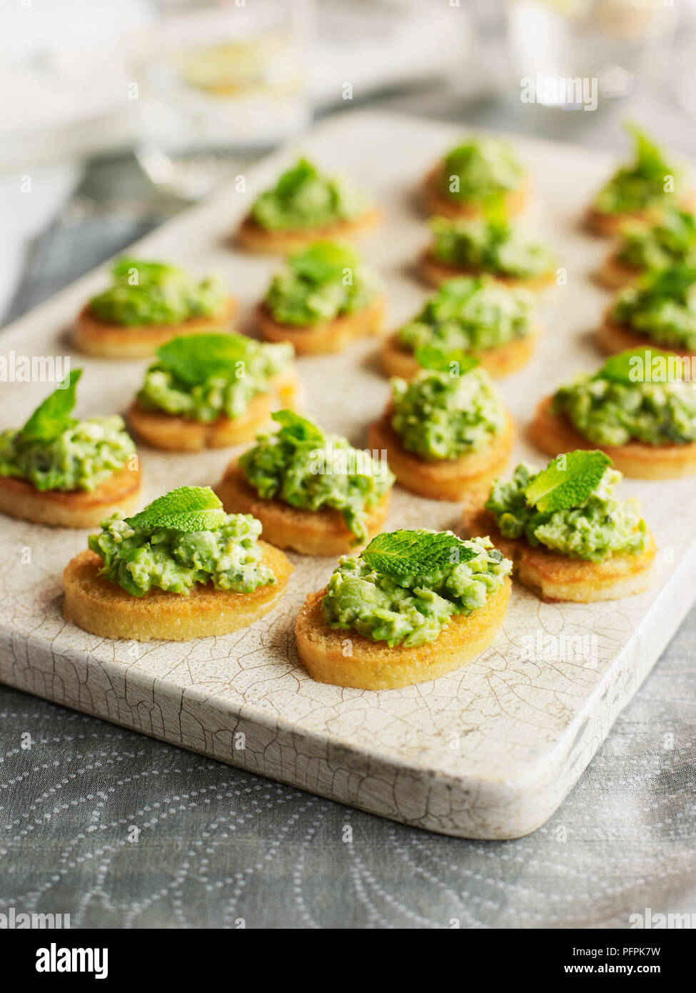 Minted aplastado de guisantes y lechuga crostini guarnecida con ramitas de menta Foto de stock