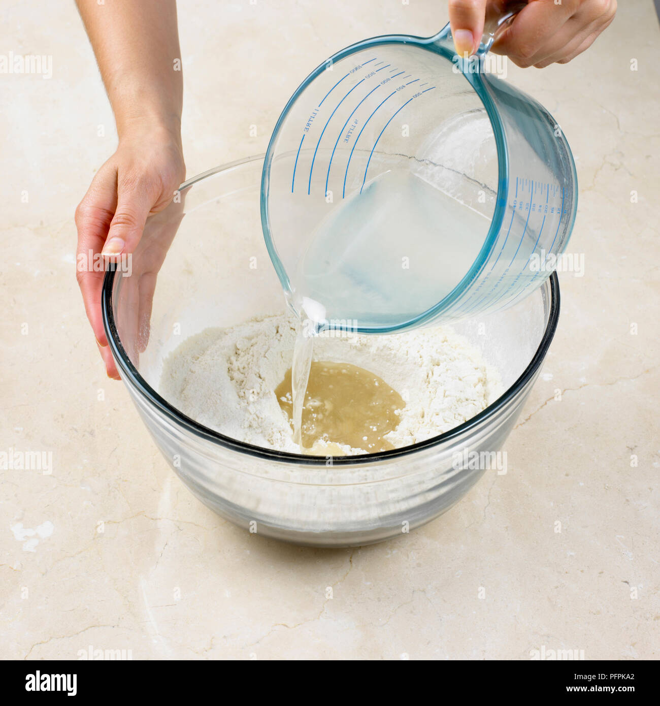 Hacer pasteles de corteza de agua caliente, verter la mezcla de grasa derretida caliente en el pozo en el centro de la mezcla de harina Foto de stock