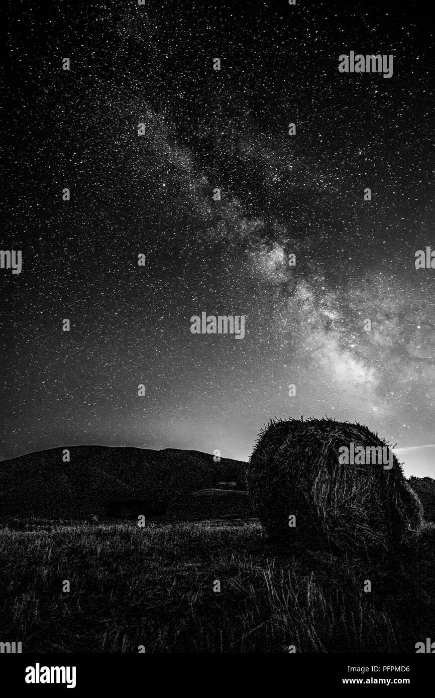 Hermosa vista del cielo nocturno estrella con la vía láctea en un campo cultivado con fardos de heno Foto de stock