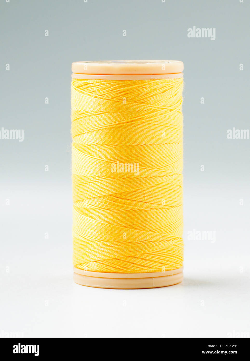 Bobina de hilo de coser de algodón amarillo Foto de stock