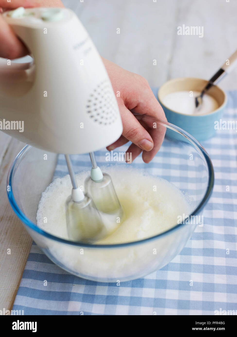 Mujer haciendo leche espumosa con batidora de mano mezclando leche en una  olla de vidrio con