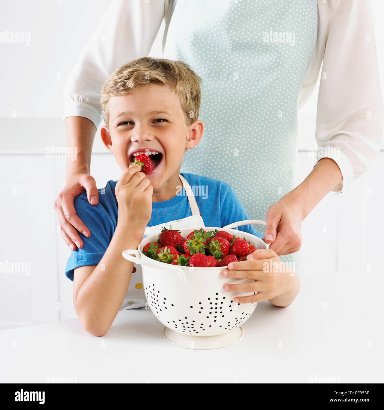 Chico con un colador de fresas, 6 años Foto de stock