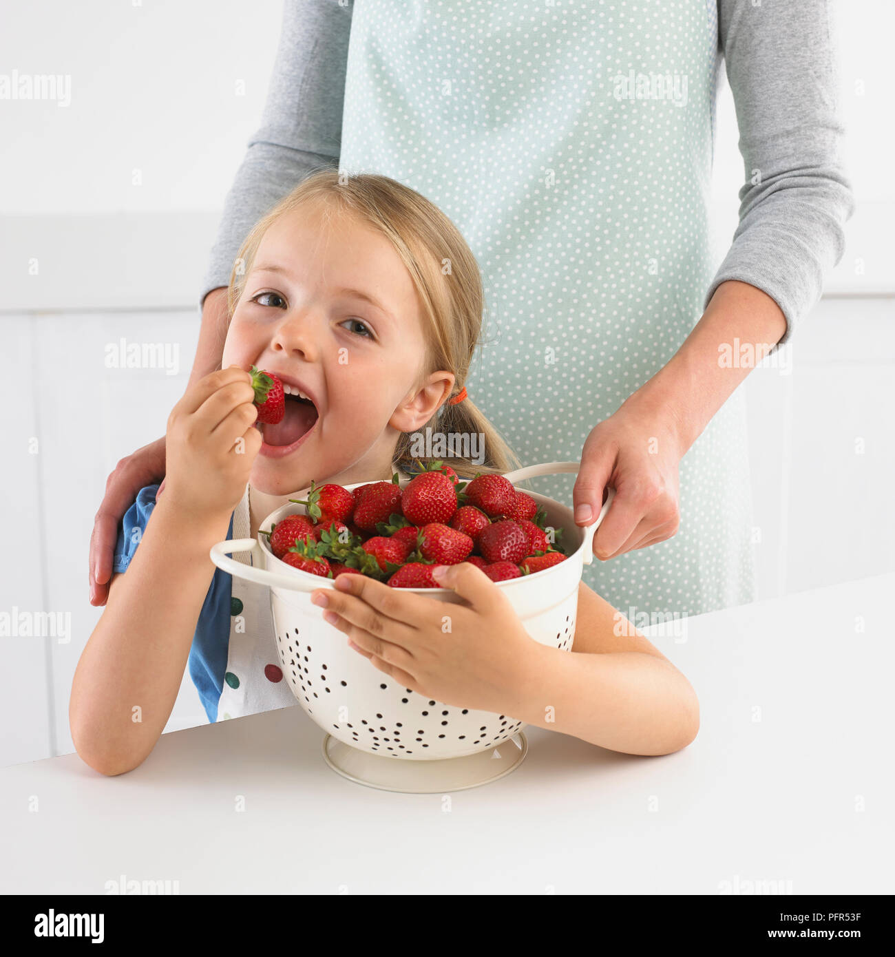 Chica sujetando un colador de fresas, 5 años Foto de stock