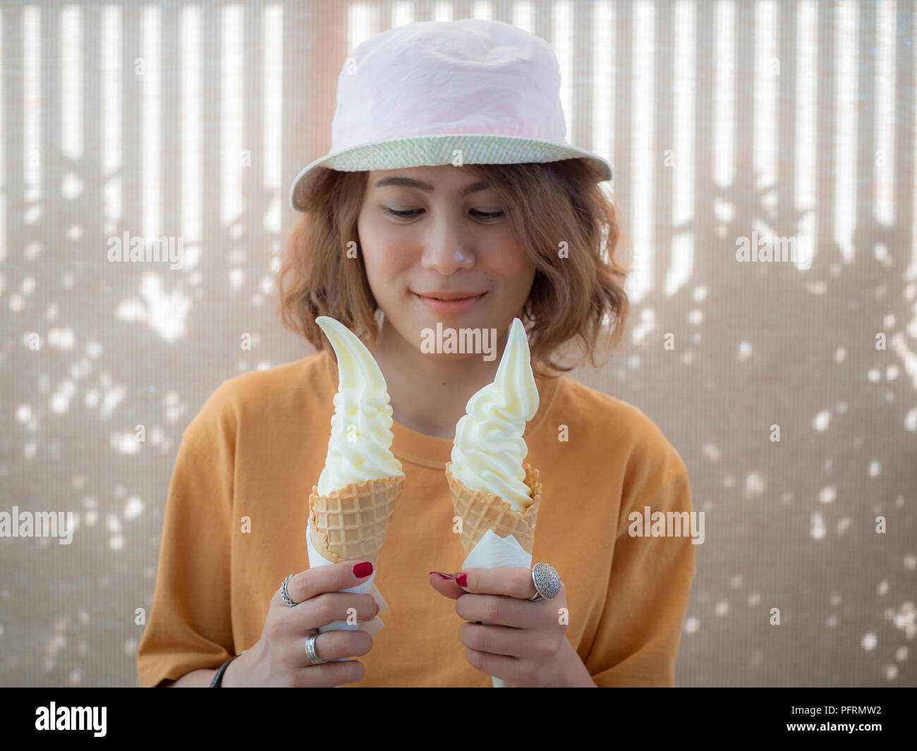 Bella Mujer Pelo Corto Vistiendo La Camiseta Amarilla Y Sombrero De Dos Tonos Suaves Sirven La Celebracion De Dos Conos De Helado De Vainilla Sobre La Hora De Verano Fotografia De Stock
