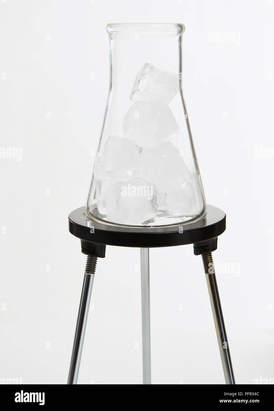 Matraz Erlenmeyer de vidrio sobre un trípode con cubitos de hielo. Foto de stock
