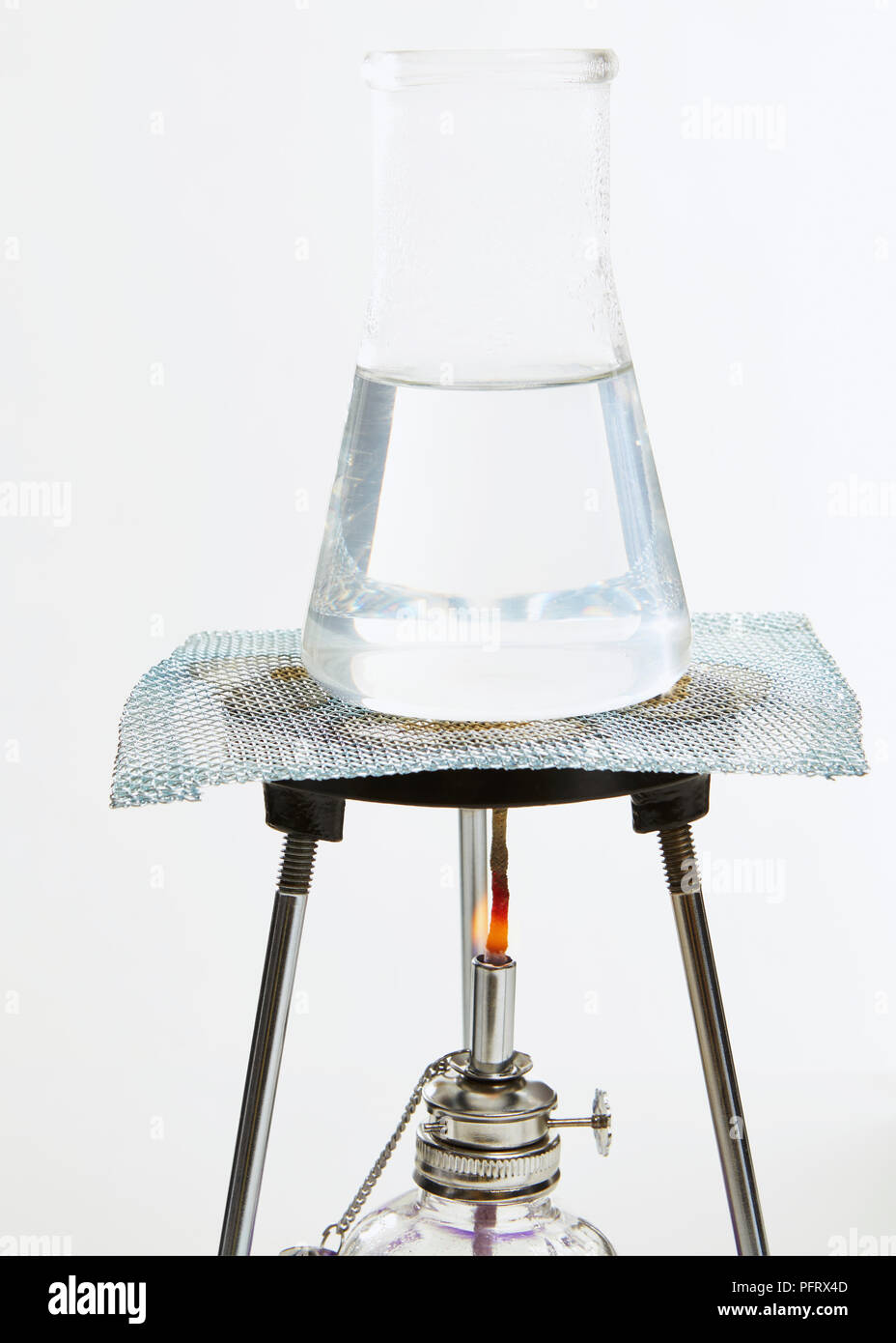 Matraz Erlenmeyer de vidrio sobre un trípode que contiene agua que se calienta Foto de stock