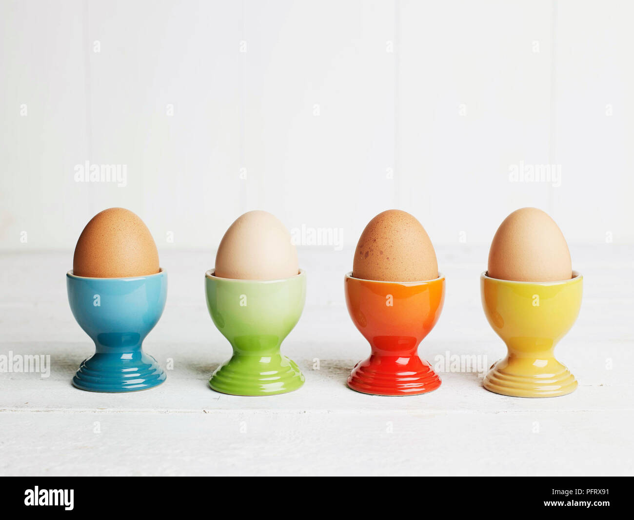 Huevos pasados por agua en tazas de huevo de color Foto de stock