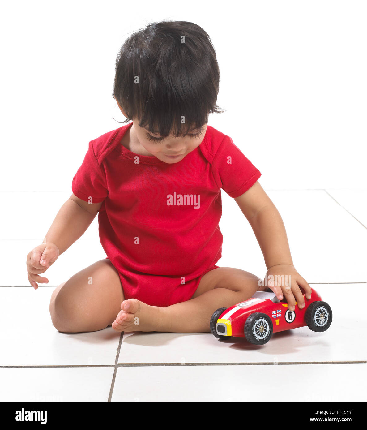 Baby Boy (16 meses) sentado jugando con coches de juguete Foto de stock