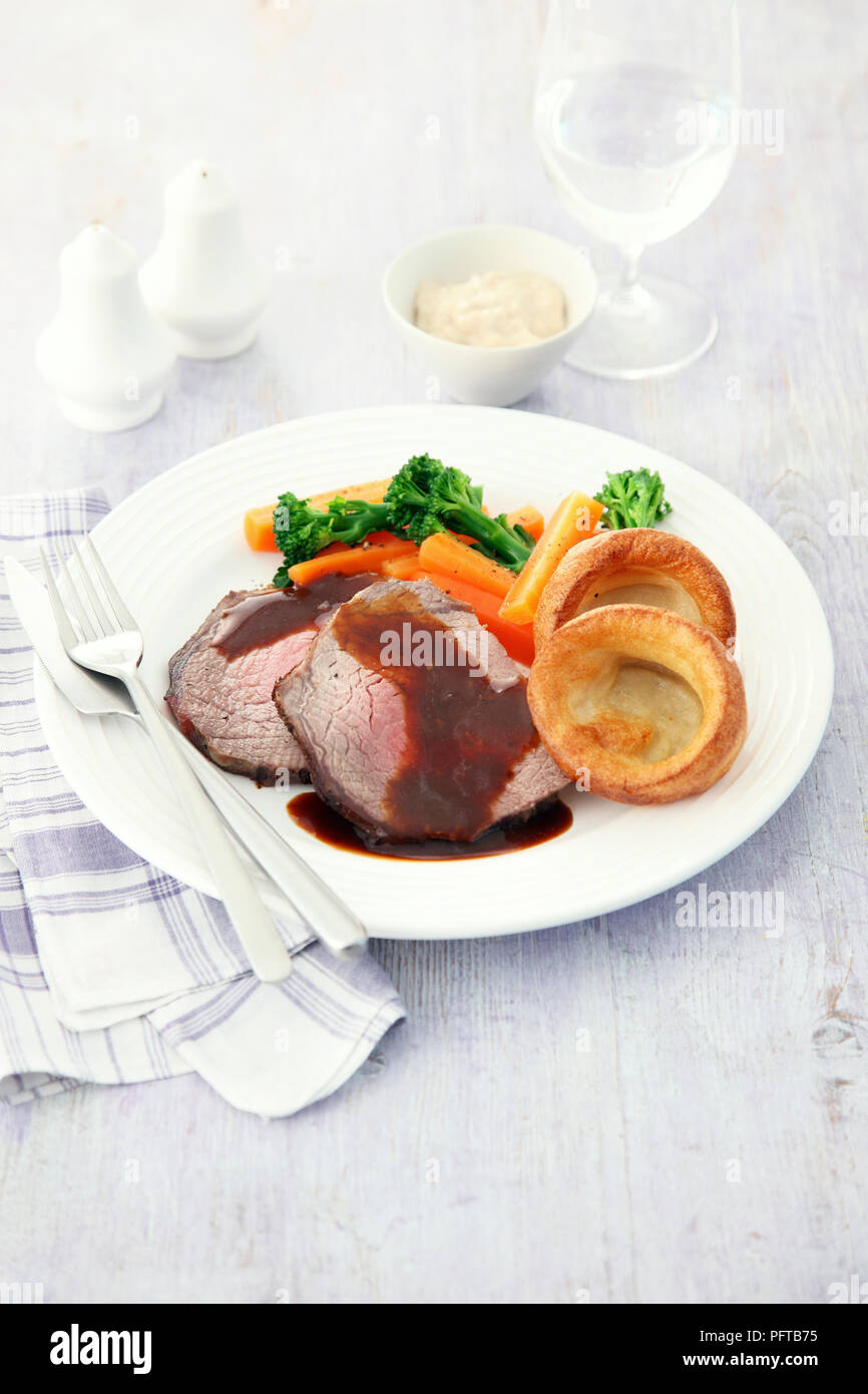 Sunday roast, asado de ternera con salsa de carne, verduras y pudines Yorkshire Foto de stock
