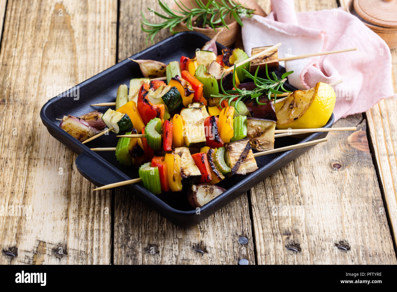 Coloridas brochetas de verduras asadas en sartén de hierro fundido. Vegan meal de verano sobre mesa de madera rústica Foto de stock