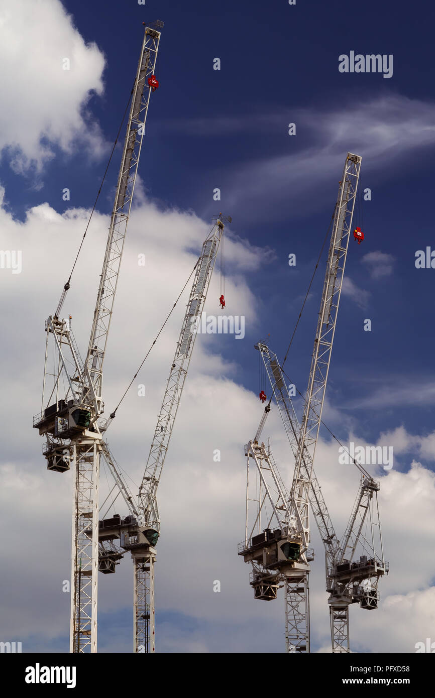 Multiplique las grúas de torre con el azul profundo del cielo azul y las nubes blancas en el fondo, en una obra en construcción en Londres, Reino Unido Foto de stock