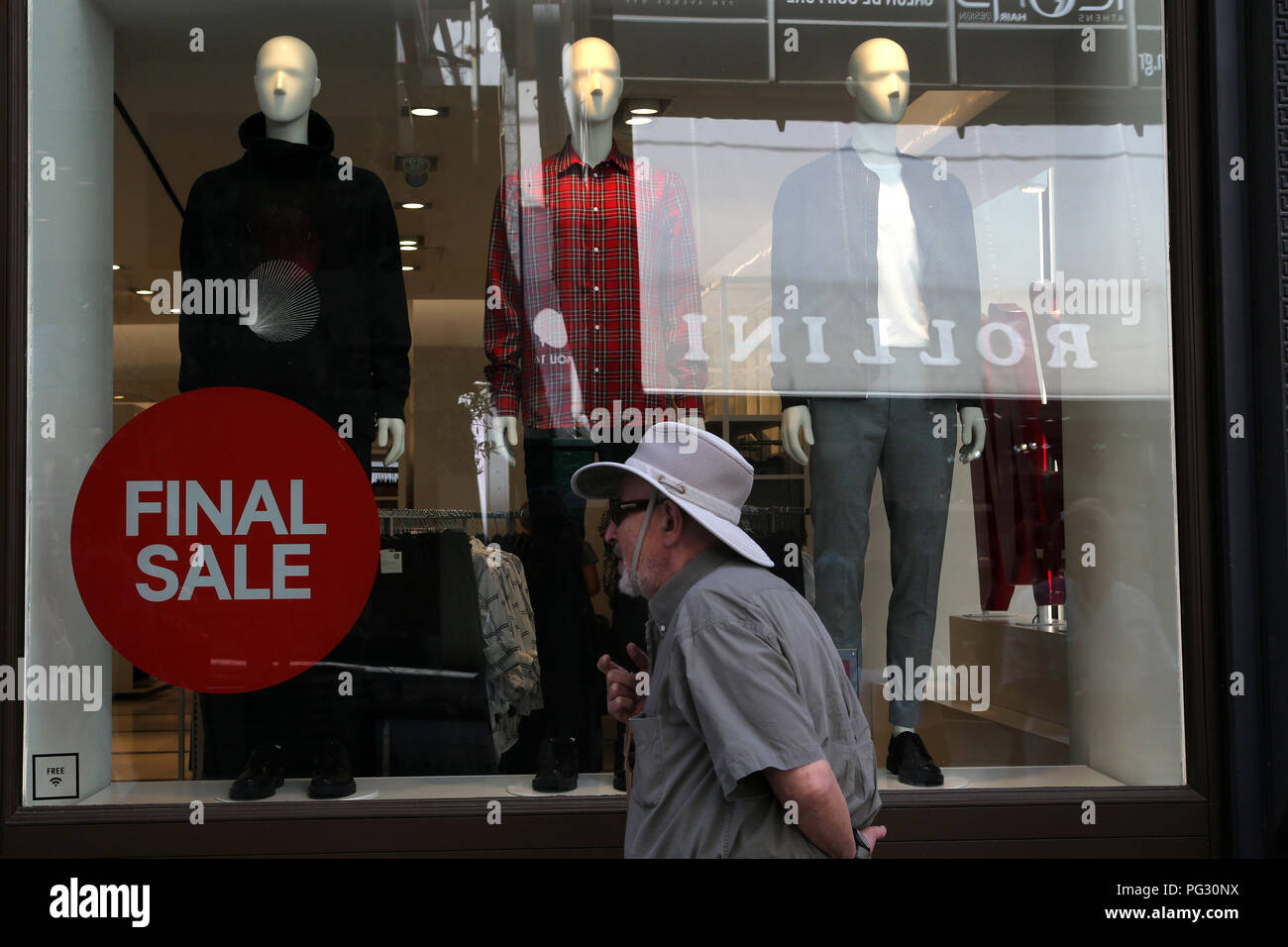 Atenas, Grecia. 22 Aug, 2018. Un hombre camina delante de una tienda durante el periodo de rebajas de verano en Atenas, Grecia, del 22 de agosto, 2018. Comercio minorista griego celebra el lunes el hito de Grecia salir del programas de financiación internacional de rescate con una mezcla de sentimientos de optimismo y preocupación por el futuro. Para ir con Feature: Griego retailing acoge a finales de los rescates con optimismo, la preocupación por el futuro crédito: Marios Lolos/Xinhua/Alamy Live News Foto de stock