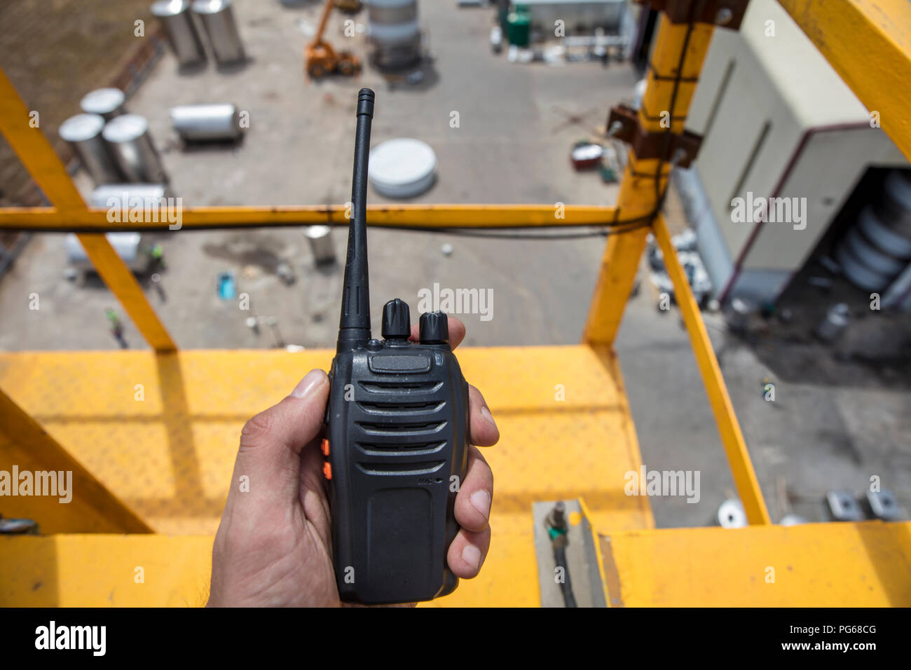 Mano sujetando el walkie talkie en la parte superior de una grúa de construcción Foto de stock