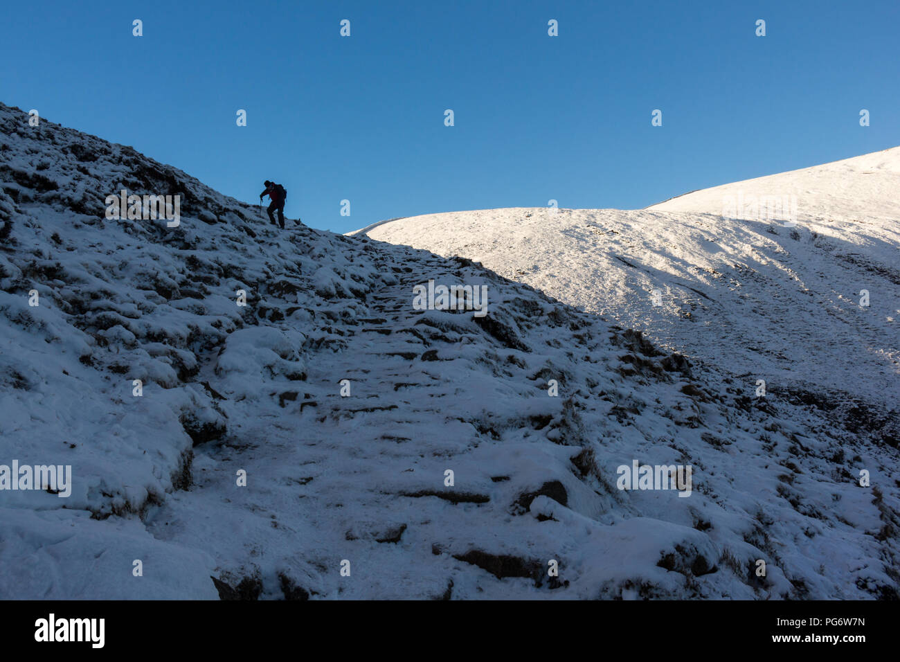 Escalador ascendente escarpados terrenos sobre la nieve y el hielo en las montañas de Mourne. Foto de stock
