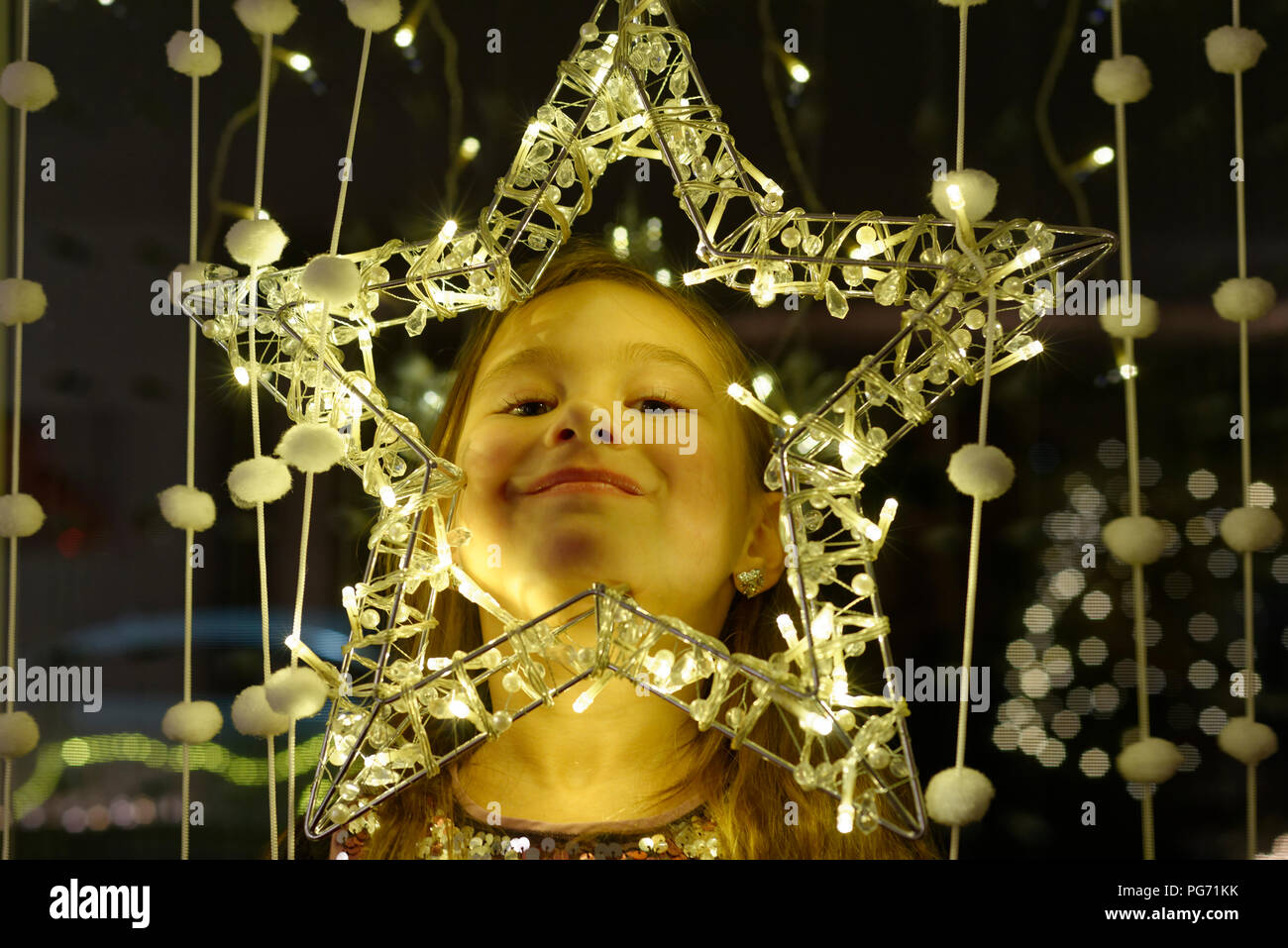 Retrato de niña sonriente mirando a través de la estrella de Navidad Foto de stock