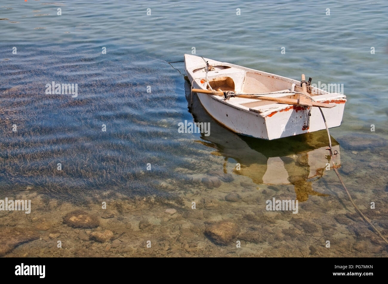 Pequeñas embarcaciones amarradas en aguas poco profundas con algas marinas protegidas Poseidonis en Mallorca, España. Foto de stock