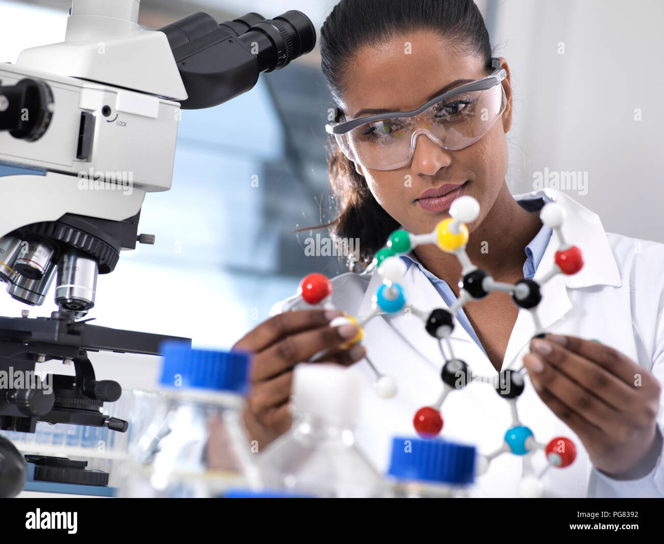 La investigación en biotecnología, investigadora examina una fórmula química utilizando una bola y un stick modelo molecular en el laboratorio. Foto de stock