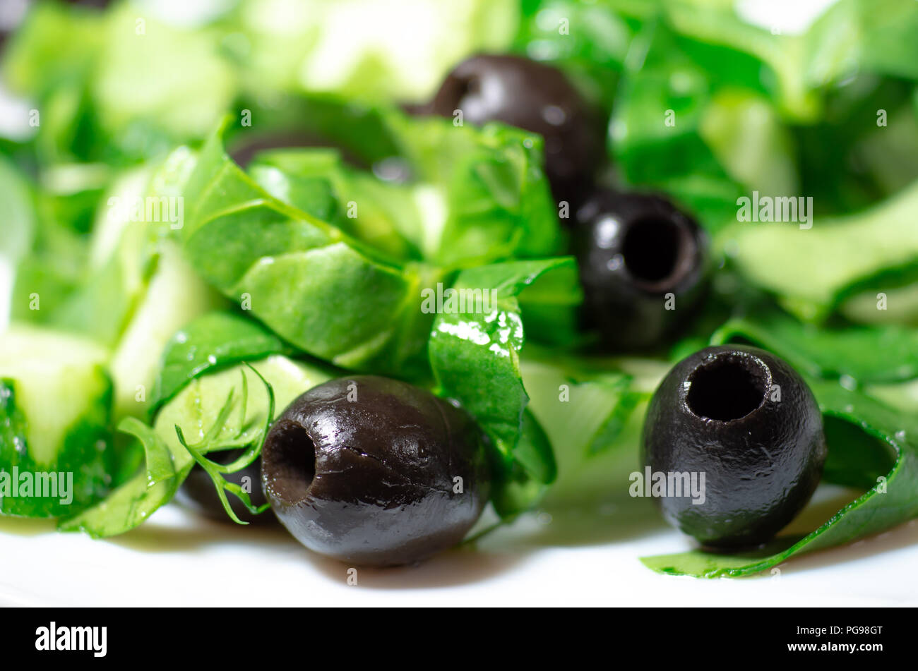 Aceitunas marinadas sin hoyos y espinacas de cerca con poca profundidad de campo. Foto de stock