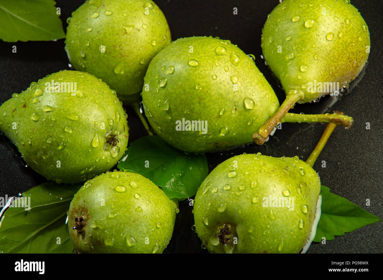 Las peras verdes sobre fondo oscuro salpicados con agua cerca Foto de stock