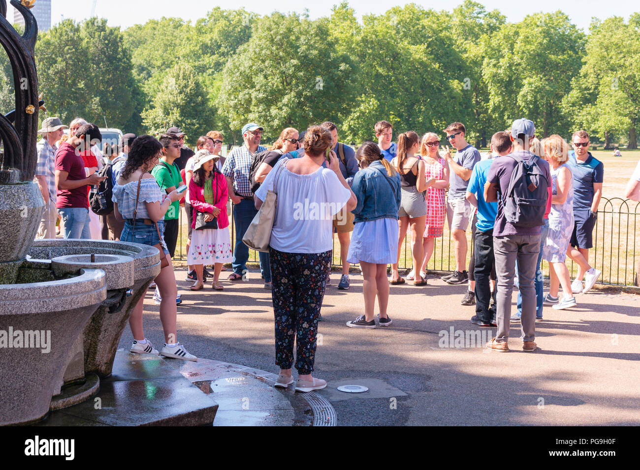 Los visitantes al parque verde recogida por parte de la fuente de agua en un día caluroso. Londres, Reino Unido Foto de stock