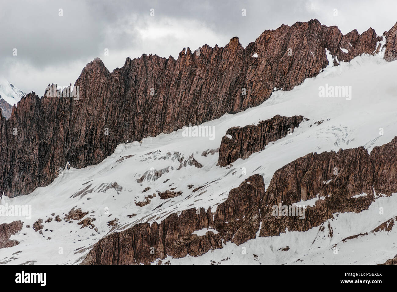 Escarpadas rocas afiladas en una montaña de nieve en un día nublado Foto de stock