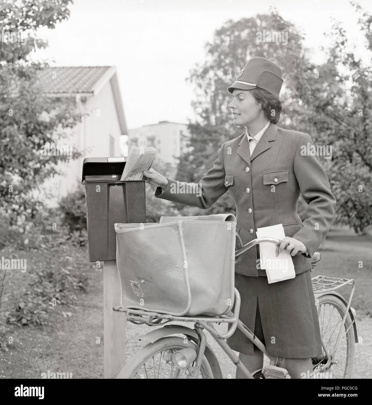 1960 cartero. Una mujer en el uniforme del servicio postal sueco ofrece  correo y poner las cartas en un buzón. Suecia 1960. Foto Kristoffersson  DG114-7 Fotografía de stock - Alamy