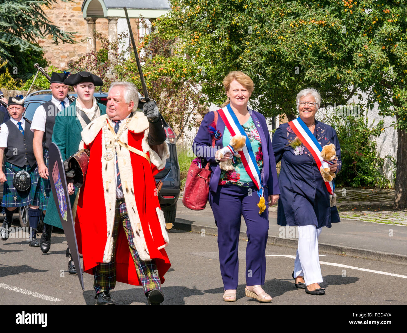 Haddington, Escocia, Reino Unido. El 25 de agosto de 2018. Haddington 700 celebraciones medievales de gran día, el día Medieval es el punto culminante de Haddington 700 eventos que tendrán lugar en 2018 para celebrar el otorgamiento de una carta por Robert Bruce a la ciudad en 1318. Eventos en todo el mercado de la ciudad incluyen un desfile. El Provost de East Lothian, John McMillan, concejal laborista escocés vestida con una túnica de armiño encabeza el desfile por la ciudad con el alcalde y el Vicealcalde de Aubigny-sur-Nere, el hermanamiento en Francia Foto de stock