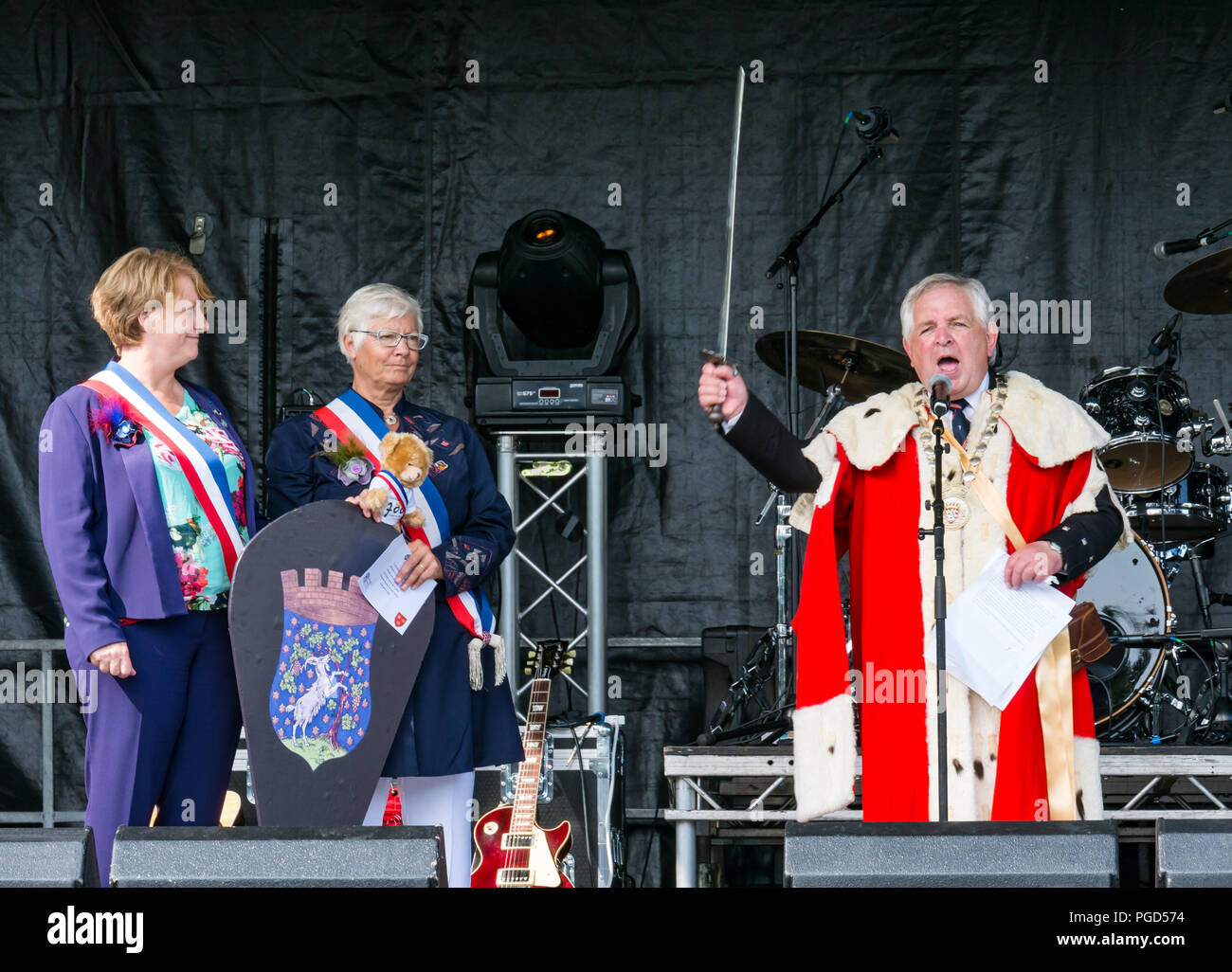 Haddington, Escocia, Reino Unido. El 25 de agosto de 2018. Haddington 700 celebraciones medievales de gran día, el día Medieval es el punto culminante de Haddington 700 eventos que tendrán lugar en 2018 para celebrar el otorgamiento de una carta por Robert Bruce a la ciudad en 1318. El provost de East Lothian, John McMillan, introduce el alcalde y el Vicealcalde de Aubigny-sur-Nere, Haddington gemelo del ciudad en Francia en el escenario de Oriente Haugh Foto de stock