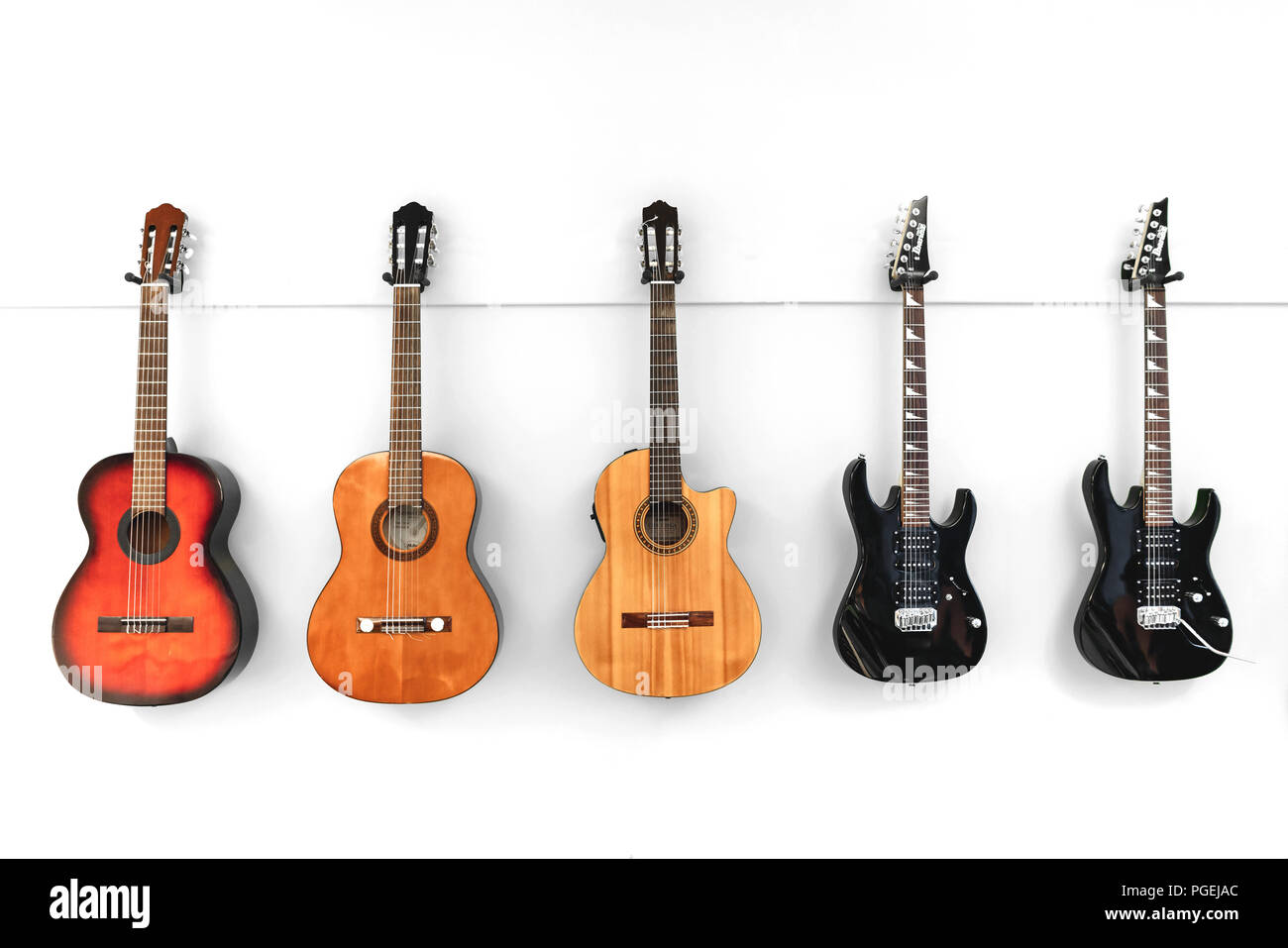 5 clásica, acústica y eléctrica, guitarras españolas colgado en una pared  blanca Fotografía de stock - Alamy