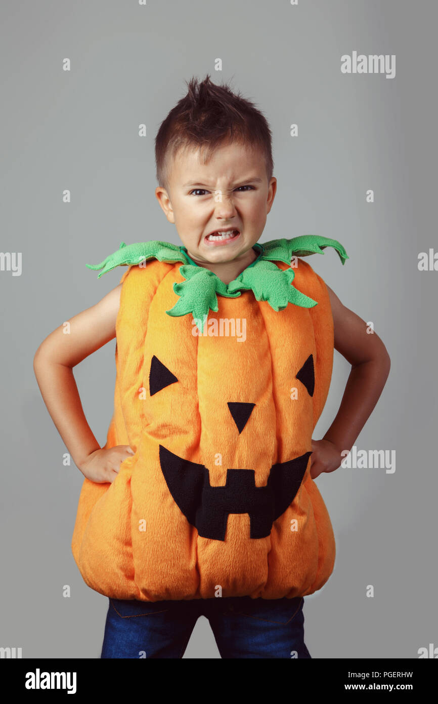 Retrato de adorables gracioso muchacho caucásico blanco vestido de calabaza de Halloween. Niño jugando a divertirse haciendo caras en studio para otoño otoño seaso Foto de stock