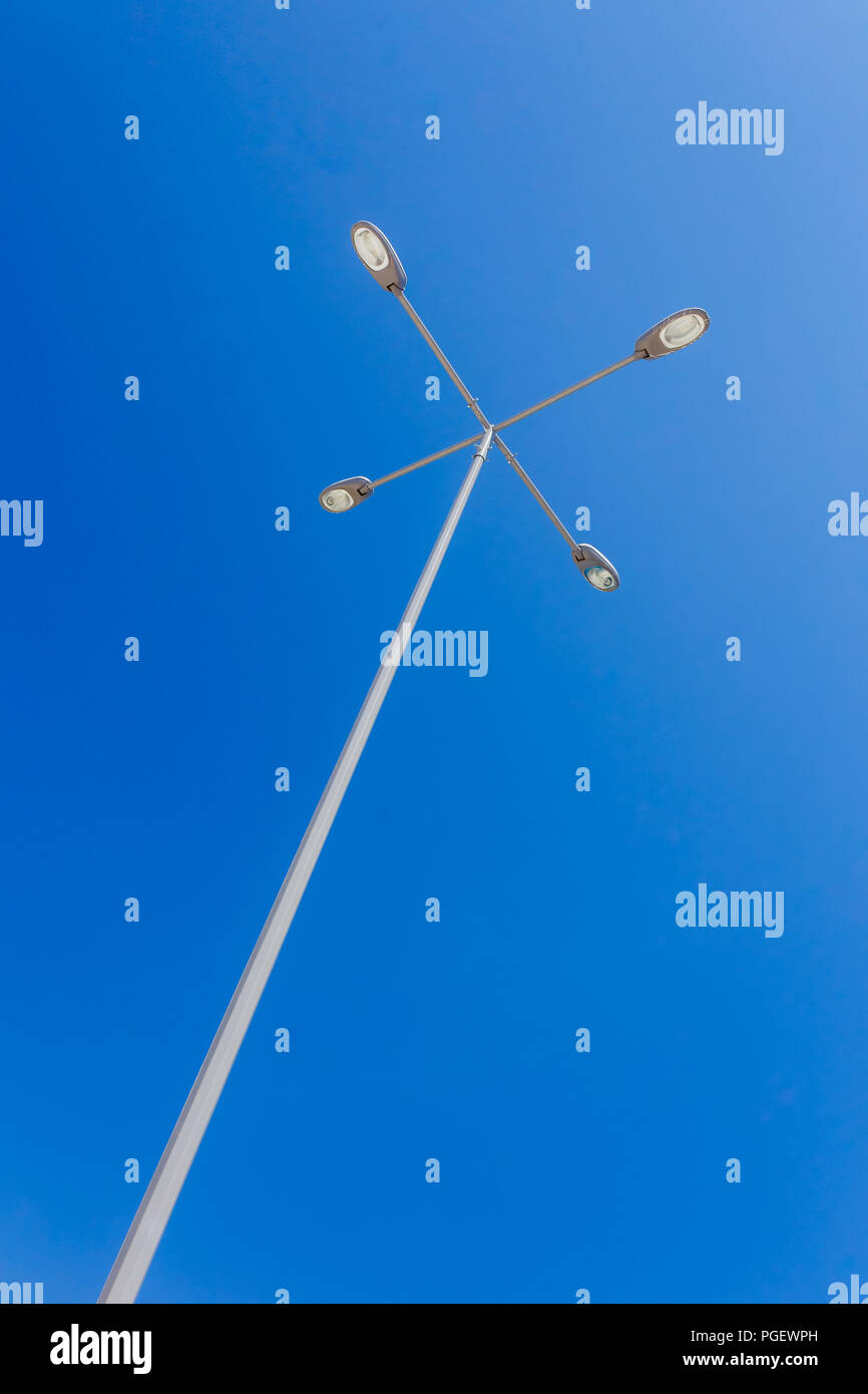 Poste de luz con 4 diferentes ramas de luz contra un cielo azul claro Foto de stock
