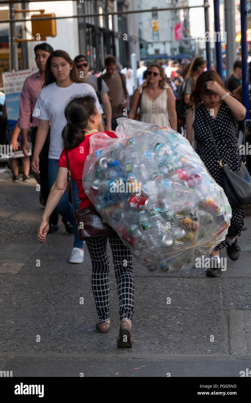 Un anónimo de mediana edad mujer asiática en la Quinta Avenida, con el depósito de las botellas que recogidos en los contenedores de basura. Manhattan, Ciudad de Nueva York. Foto de stock
