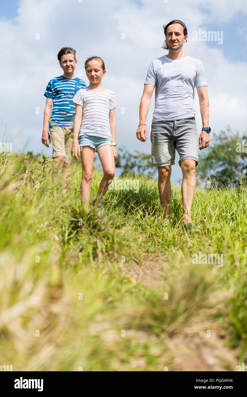 Familia de padre y dos hijos disfrutando tranquilo paseo al aire libre en verano Foto de stock