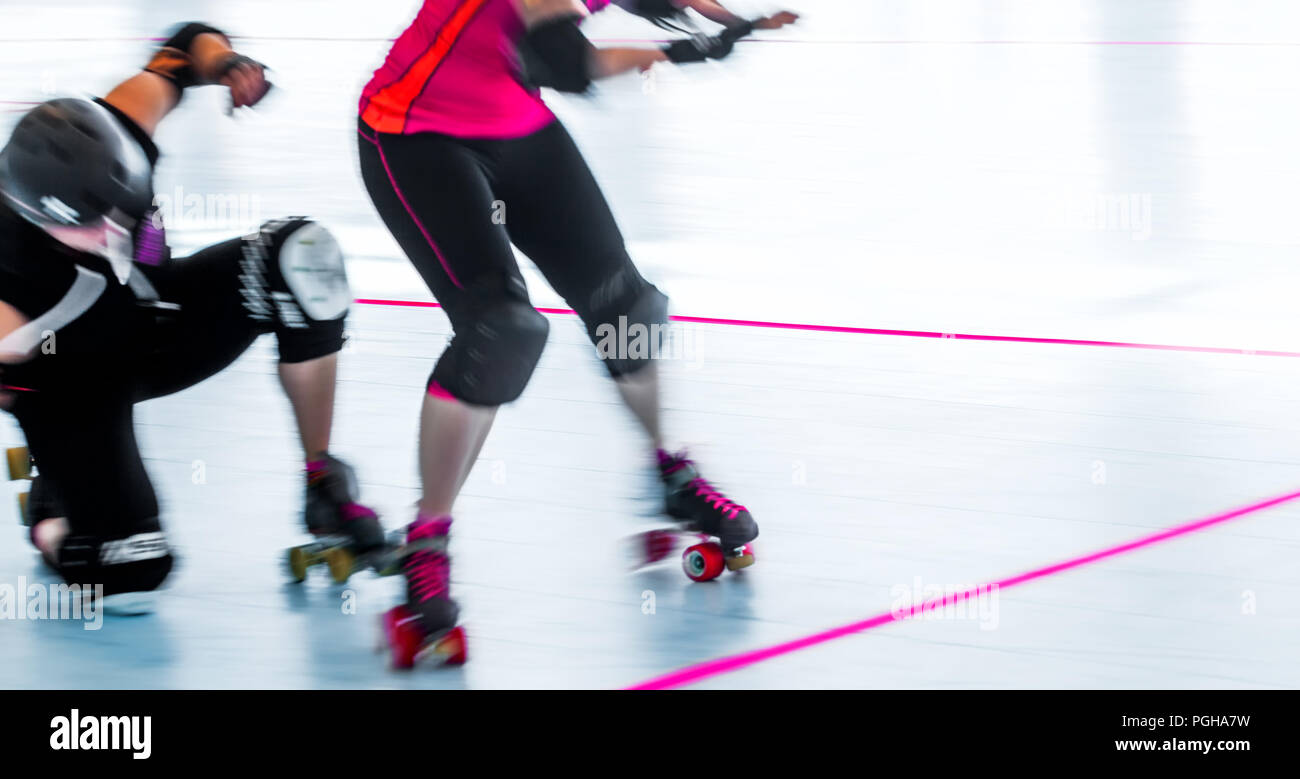 Roller derby patinadores cerca de desenfoque de movimiento pan de acción de disparo. Un patinador cae de rodillas. Foto de stock
