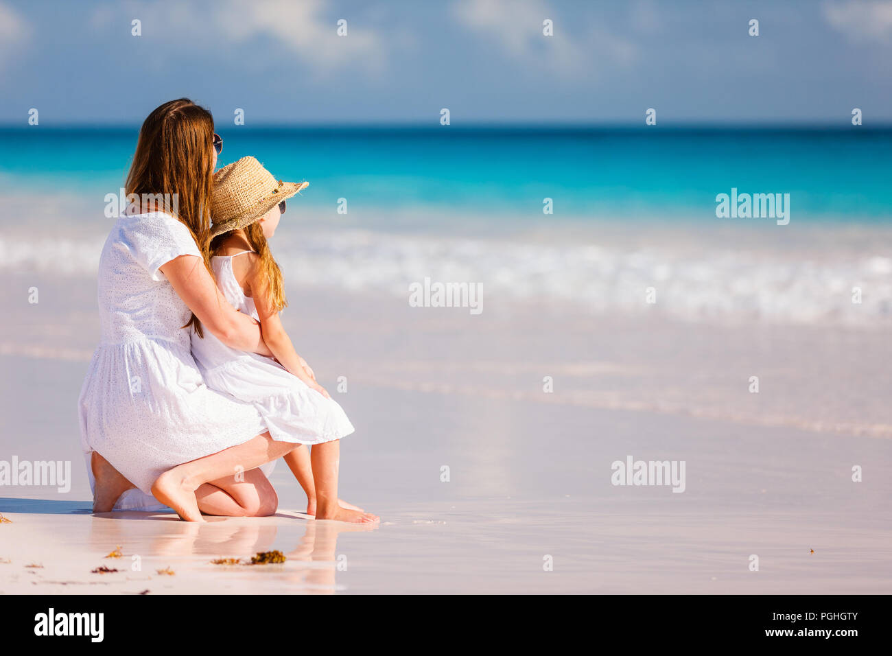 Vista posterior de la madre y la hija en la playa del Caribe Foto de stock