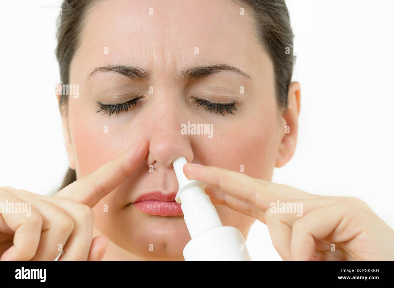 Una mujer joven con aerosol nasal, cubriendo las fosas nasales Foto de stock