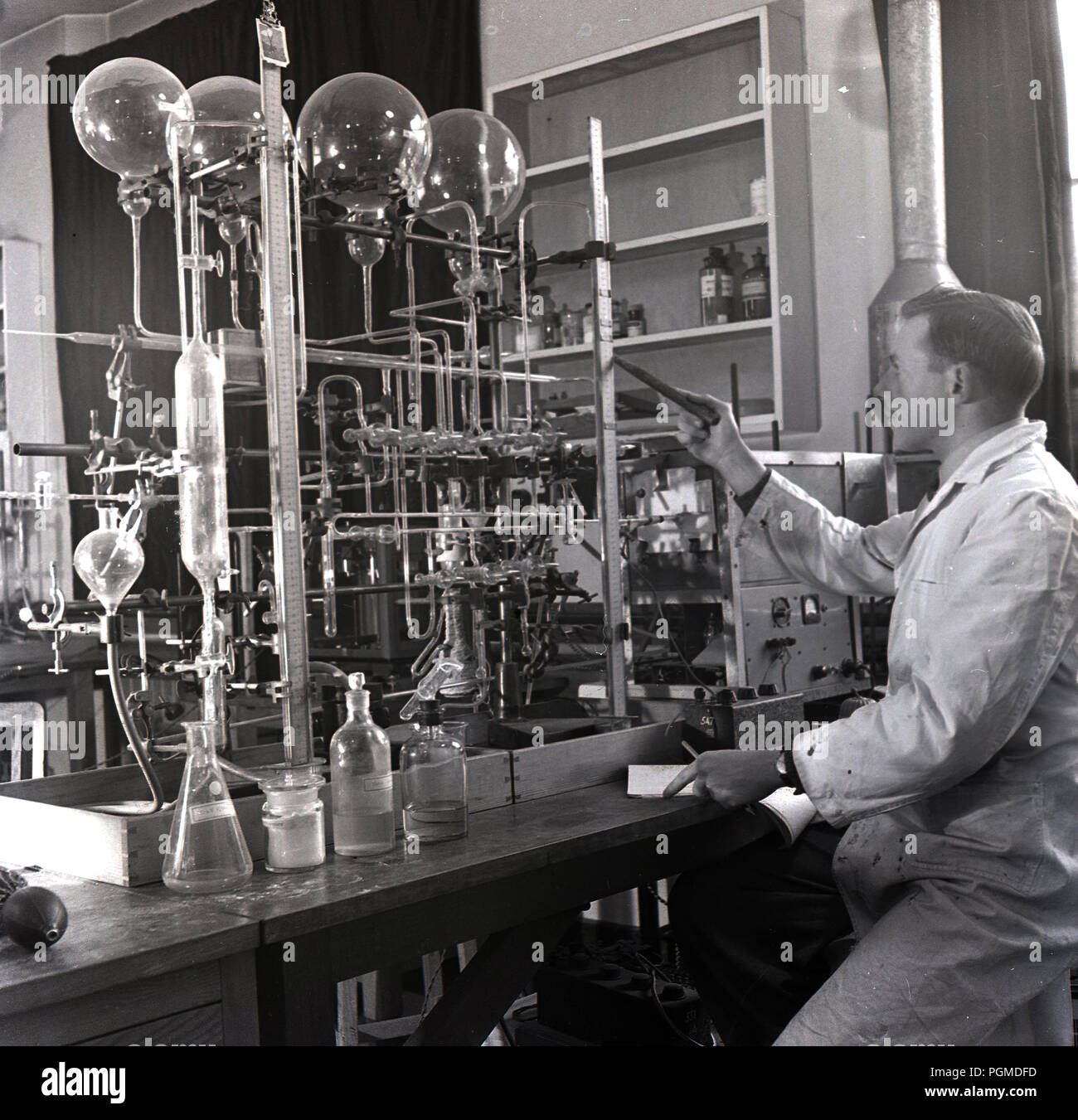 1950, histórico, científico masculino en bata blanca en un laboratorio de trabajo con numerosos tubos de ensayo de vidrio en Oxford univ, para probar o investiage reacciones gaseosas, Oxford, Inglaterra, Reino Unido. Foto de stock