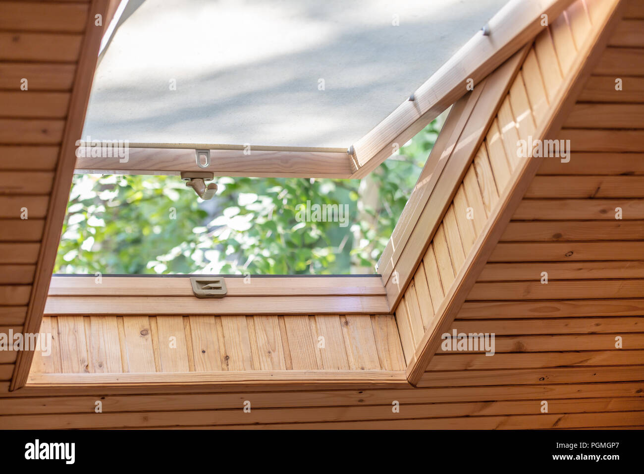 Abrir ventana de techo con persianas o cortinas en casa de madera de la  buhardilla. Habitación con techo inclinado hechas de materiales ecológicos  naturales y vistas al parque a través de abierto