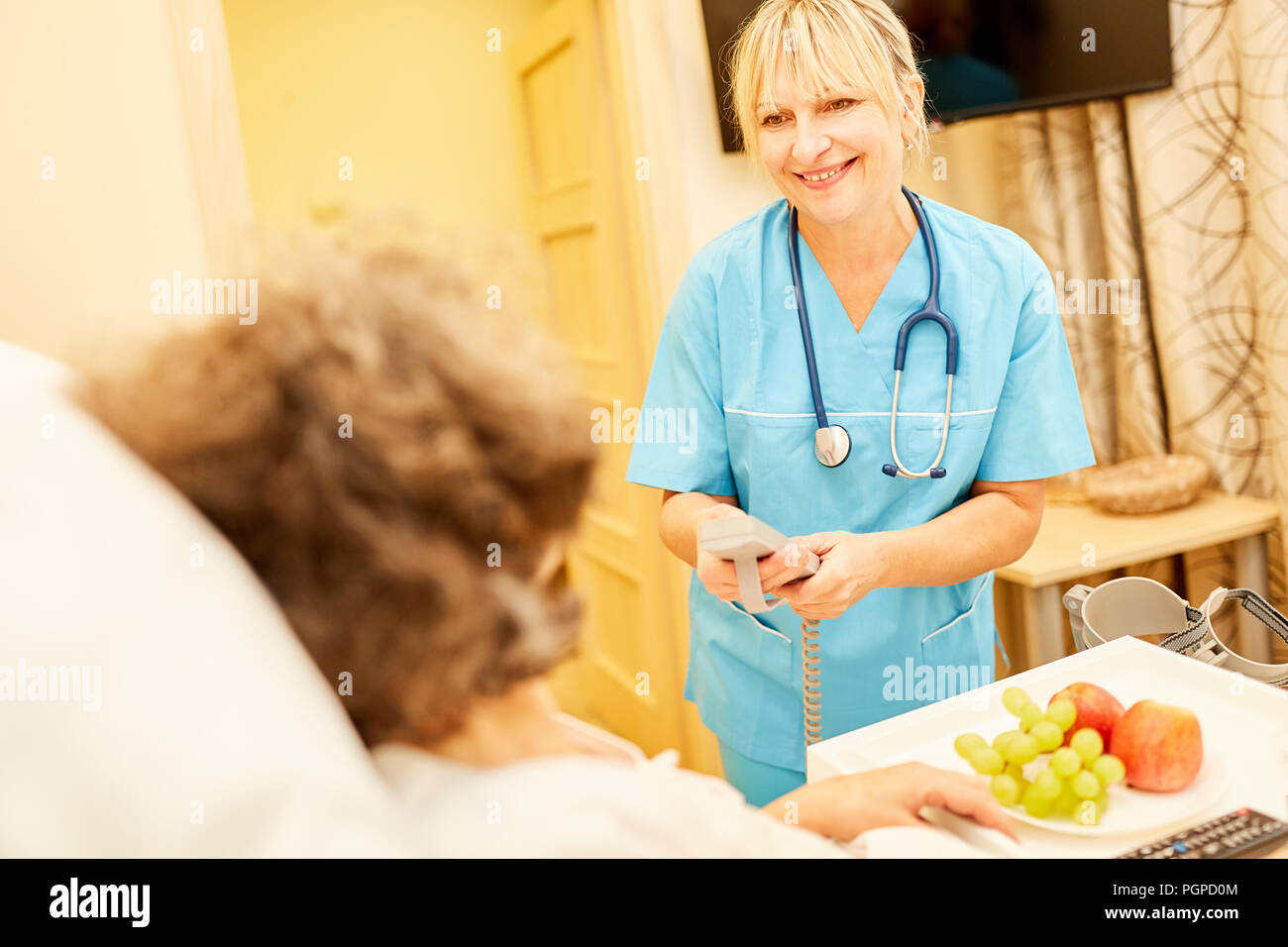 La Enfermería Mujer trae altos sano desayuno a la cama de cuidados en el hogar Foto de stock
