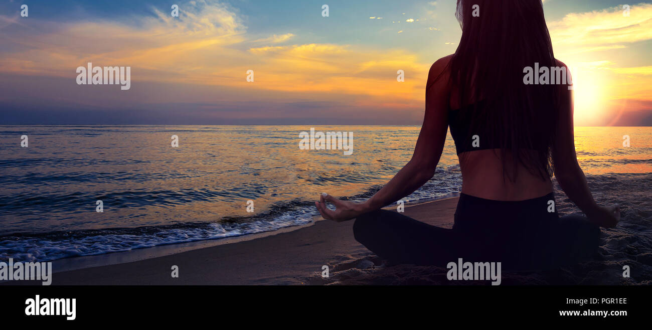 La meditación del yoga banner - mujer en una pose de loto en una playa  junto al mar sobre un fondo de un pintoresco paisaje al atardecer (copia  espacio Fotografía de stock -
