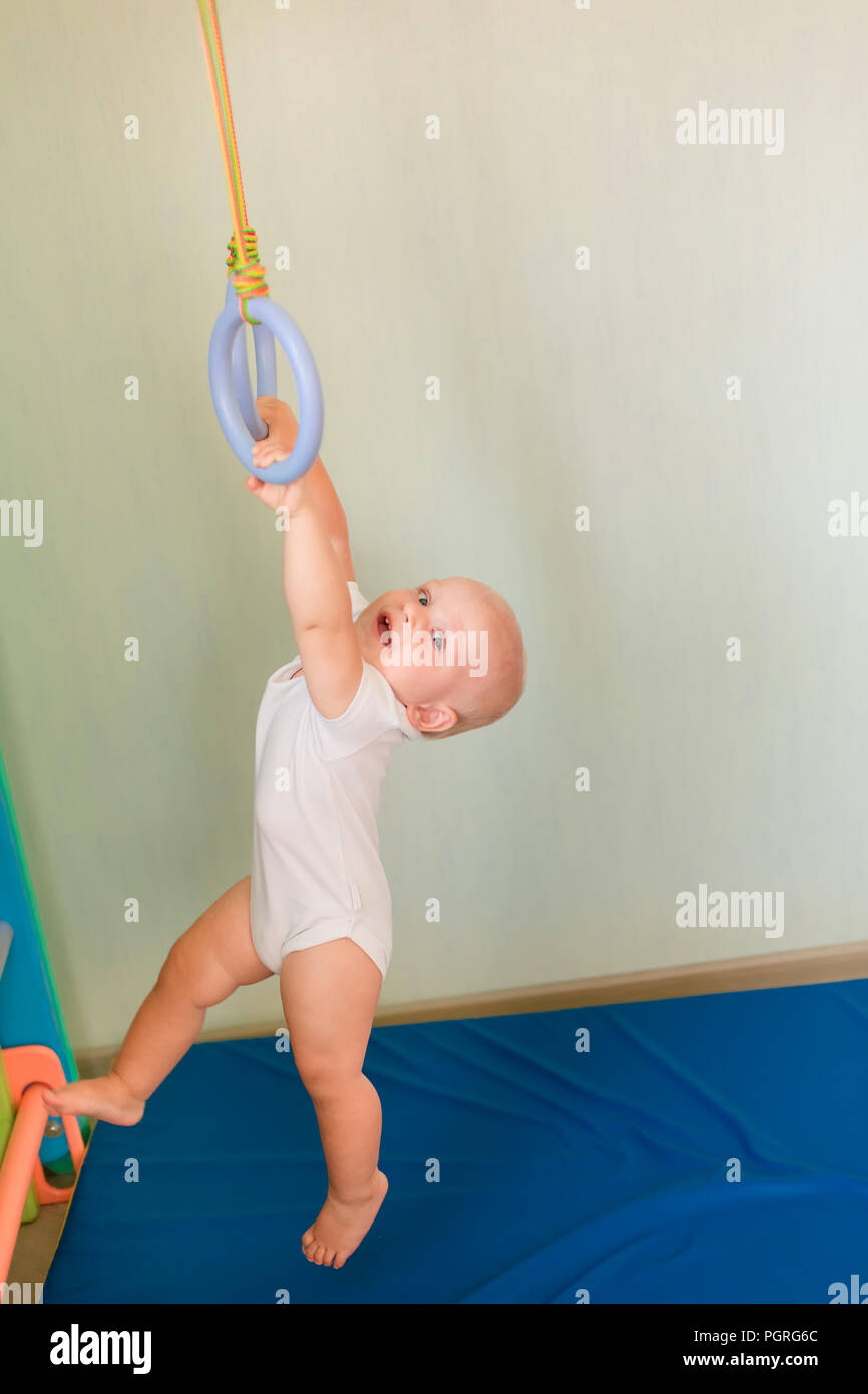 Cute Baby Boy colgando de los anillos en casa muro gimnasio. Bebé temprano  concepto de desarrollo deportivo Fotografía de stock - Alamy