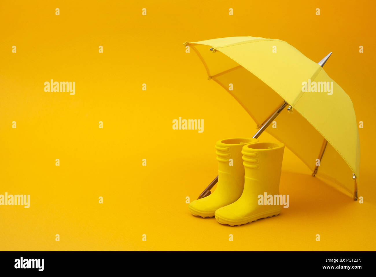 Un par de botas de lluvia amarillas y una sombrilla, sobre un fondo  amarillo Fotografía de stock - Alamy
