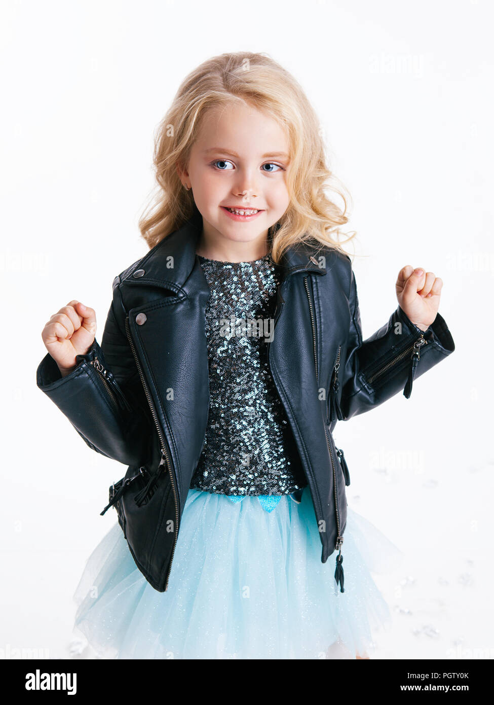 Hermosa niña con cabello rizado rubio peinado emplazamiento sobre la fiesta  en vestido con lentejuelas y chaqueta negra. Lámina de aluminio en el  suelo. Concepto Fotografía de stock - Alamy