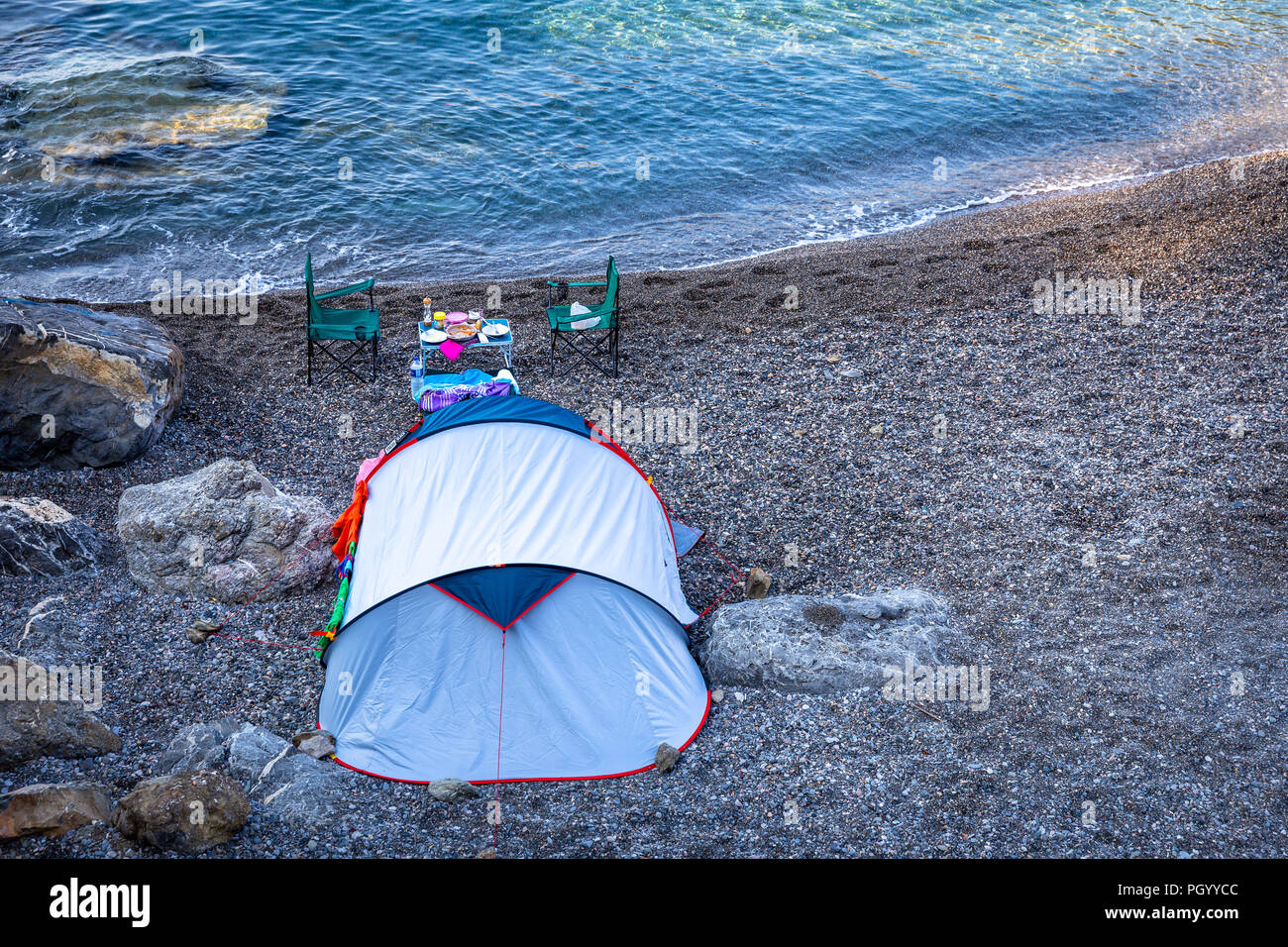 Concepto de acampada en una playa vacía en un cielo bay. Camping carpa, sillas y mesa con hermosas vistas al mar y a fondo del cielo. Foto de stock