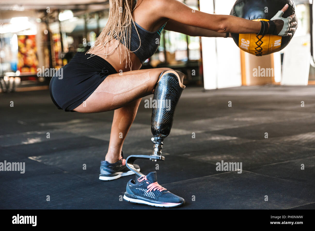 Retrato de hermosa inválido con prótesis sportswoman chándal en cuclillas  con bola de fitness en el gimnasio crossfit Fotografía de stock - Alamy